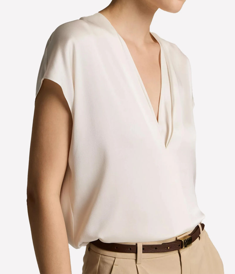 A close-up of a model wearing a short-sleeve cream-colored blouse