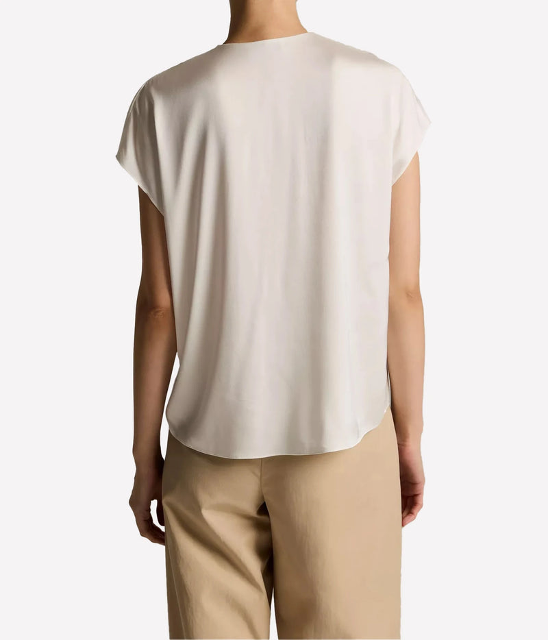 A person shown from the back wearing a light cream short-sleeve top