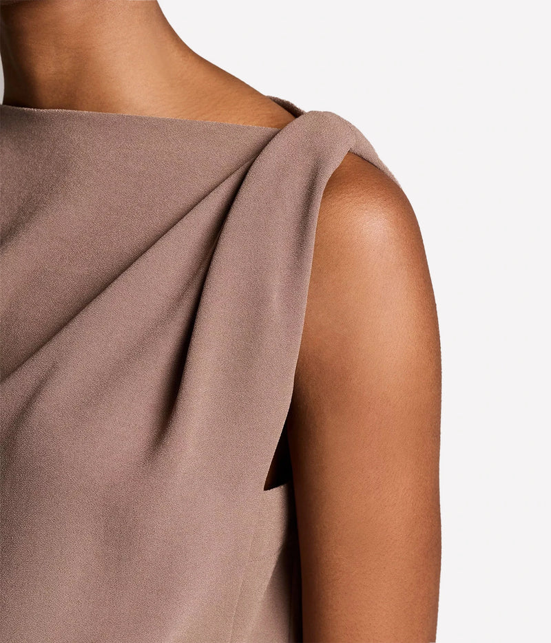 Close-up of a model wearing a draped, off-the-shoulder sleeveless top in a dusty taupe-brown color