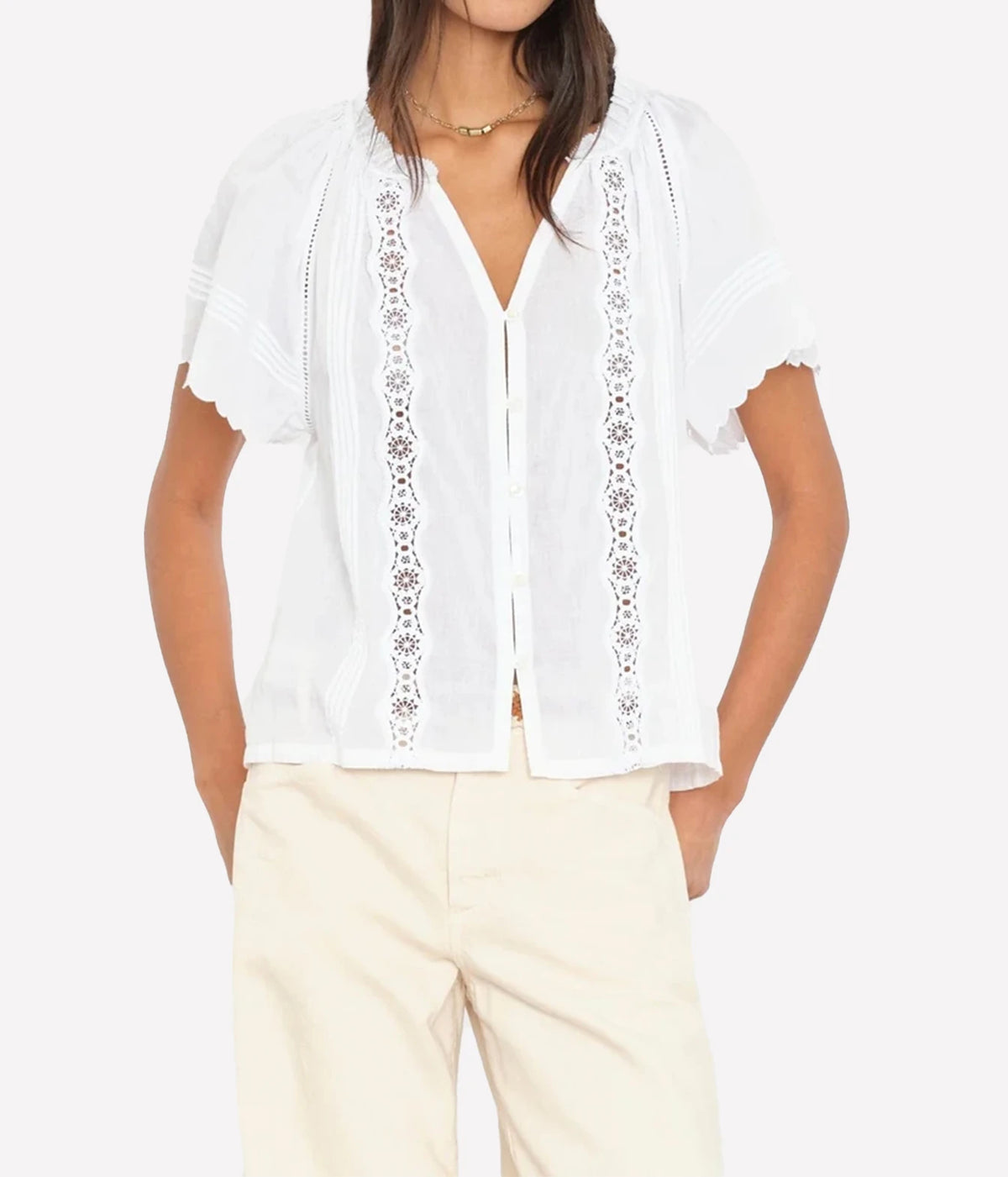 Woman wearing a white button-front blouse with flutter sleeves and beige coloured pants