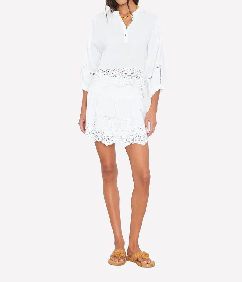 A woman modeling the Xirena Roxana blouse in white and matching Xirena Rima Skirt in White skirt set.