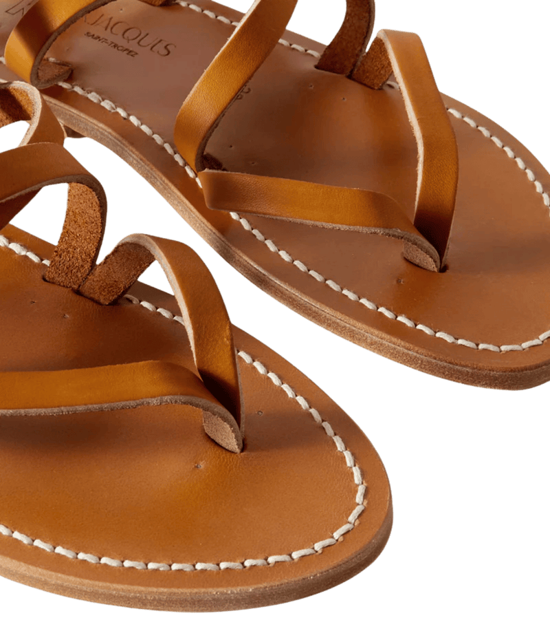 Pair of brown leather sandals with white stitching on a transparent background