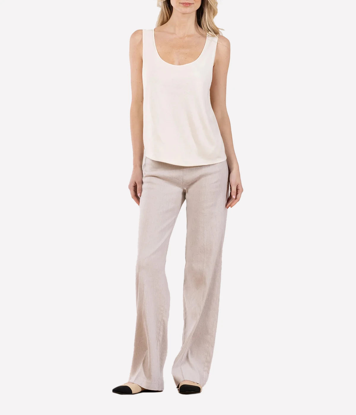 Model in a cream silk tank top and silky taupe pants on a white background.