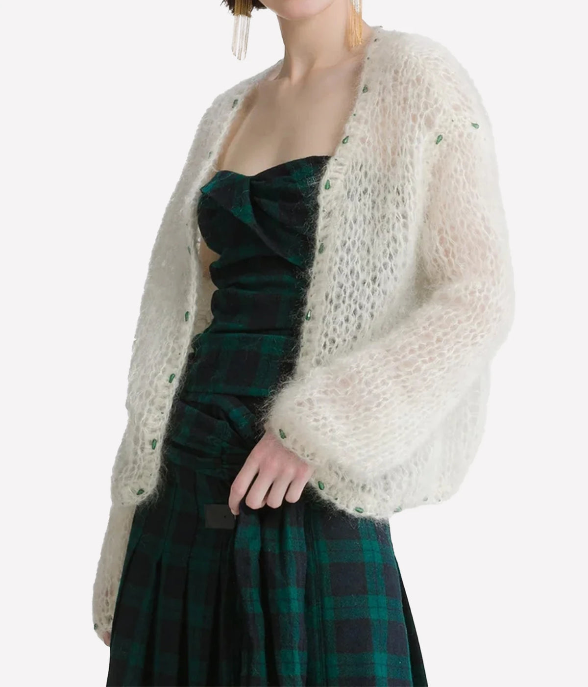 Woman wearing the Forte Forte mohair cardigan in Jewel Ivory over a green tartan strapless dress, front three-quarter view.