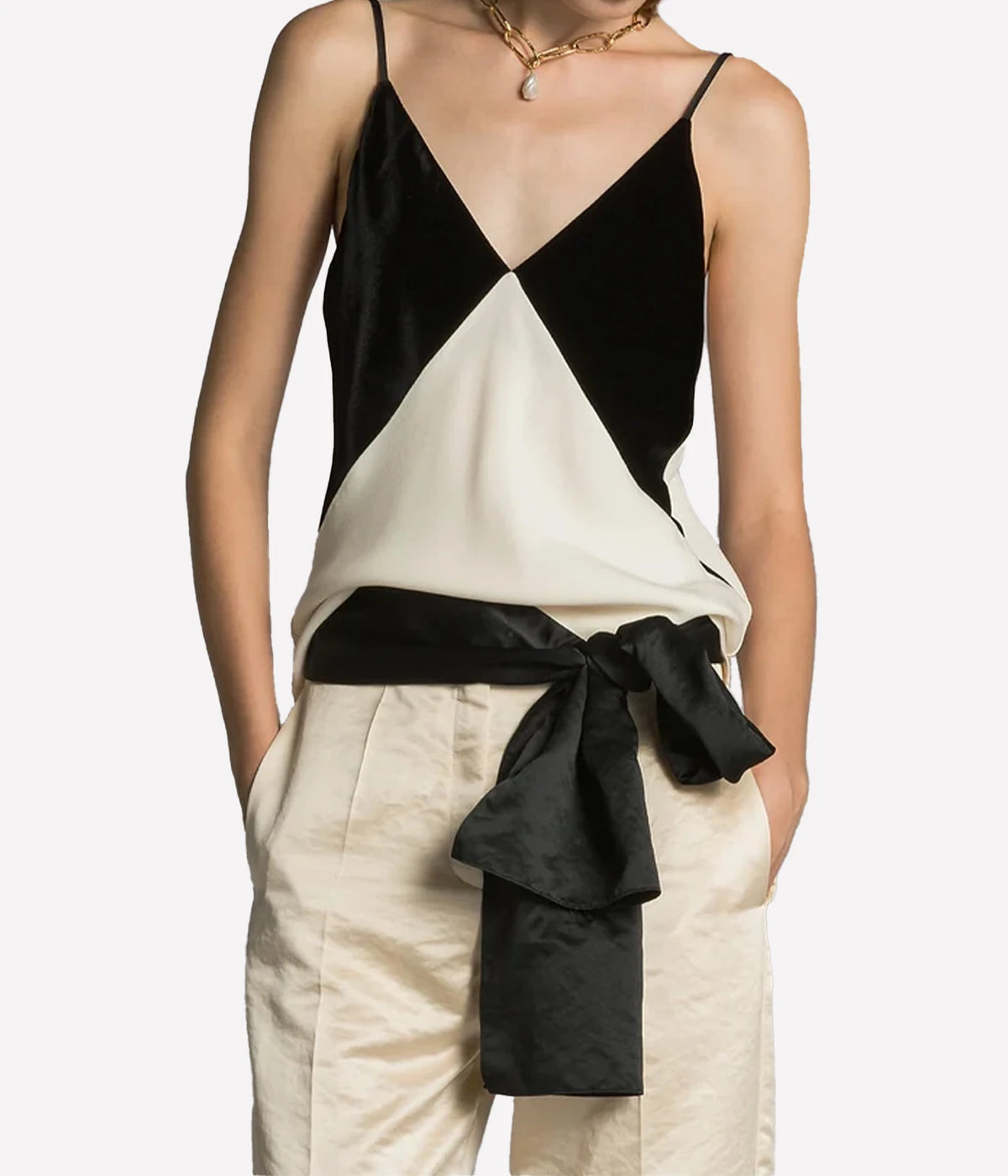 Woman wearing the Forte Forte satin and velvet slip top in Diamond with cream trousers and a black sash tied at the waist, front view.