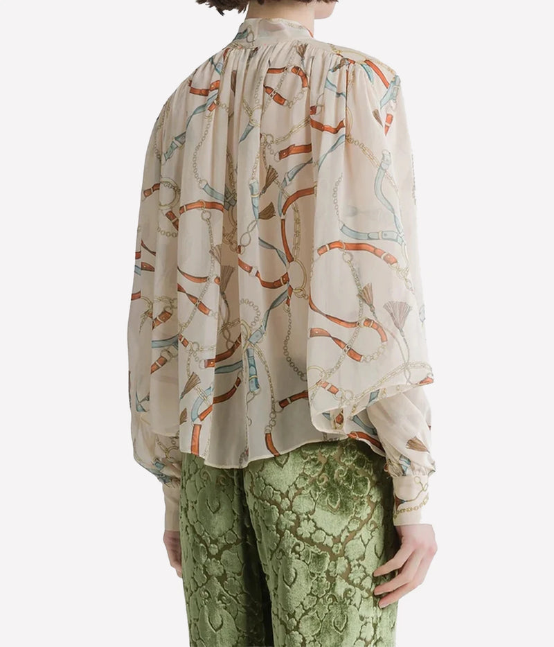 Back view of the Forte Forte crown print silk shirt in Ivory, worn with green trousers.