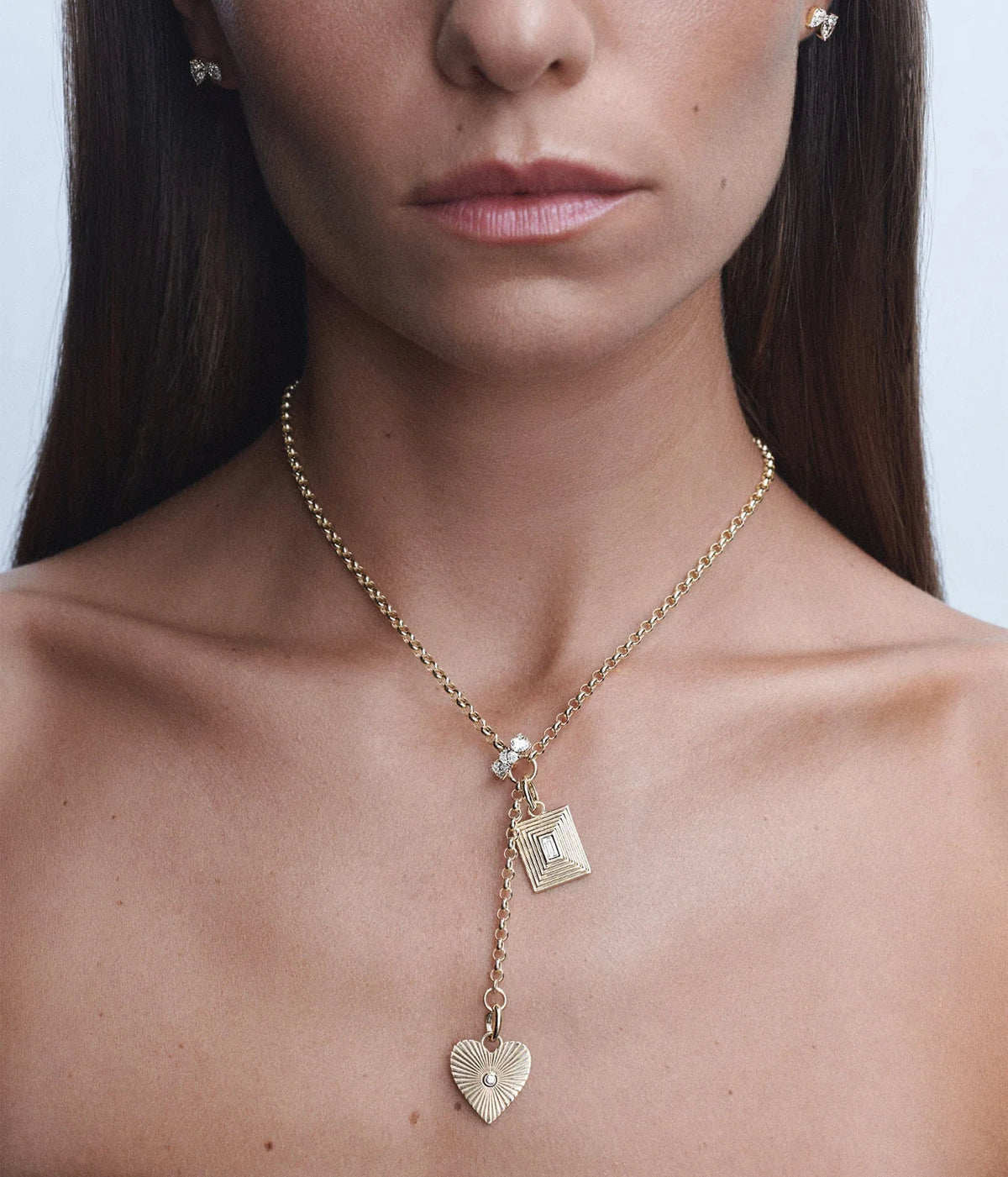 Model wearing the Adina Reyter Groovy Diamond Heart Rays Hinged Charm in 14K Yellow Gold on layered gold chains with a diamond charm