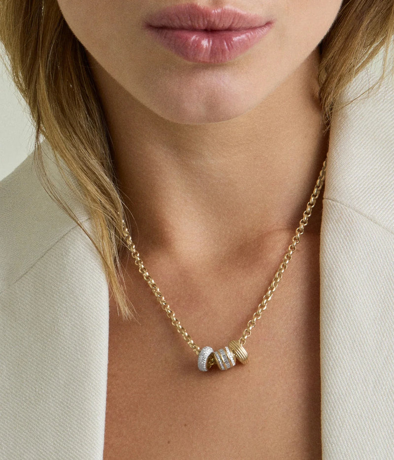 Model in a white blazer wearing the Adina Reyter Groovy Spacer Big Bead in 10K Yellow Gold alongside other beads on a gold chain