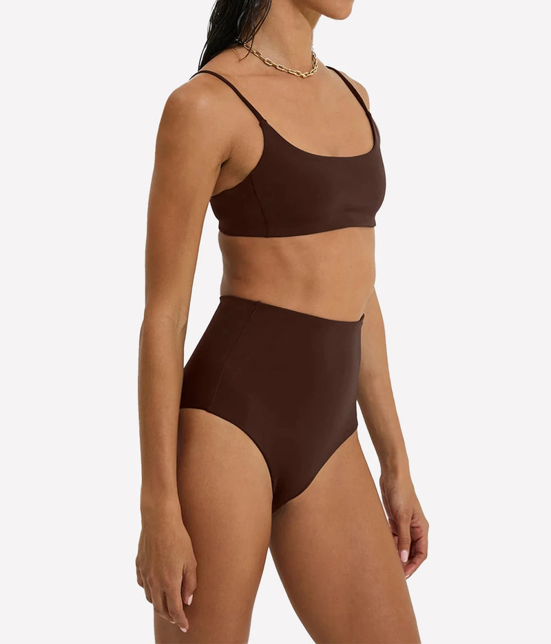 A woman modeling a matching two-piece swimsuit in a solid dark brown color, featuring a scoop-neck bikini top and high-waisted bikini bottoms, Hi Tide Bottom In Cold Brew