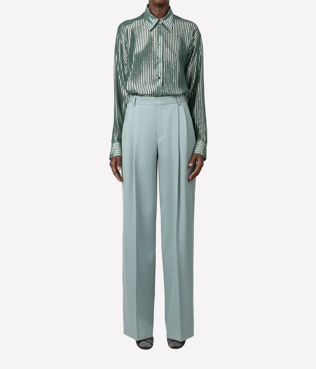 A model wearing a green and white vertically striped long-sleeve button-up shirt paired with high-waisted, wide-leg sage green trousers, shown against a plain light gray background.