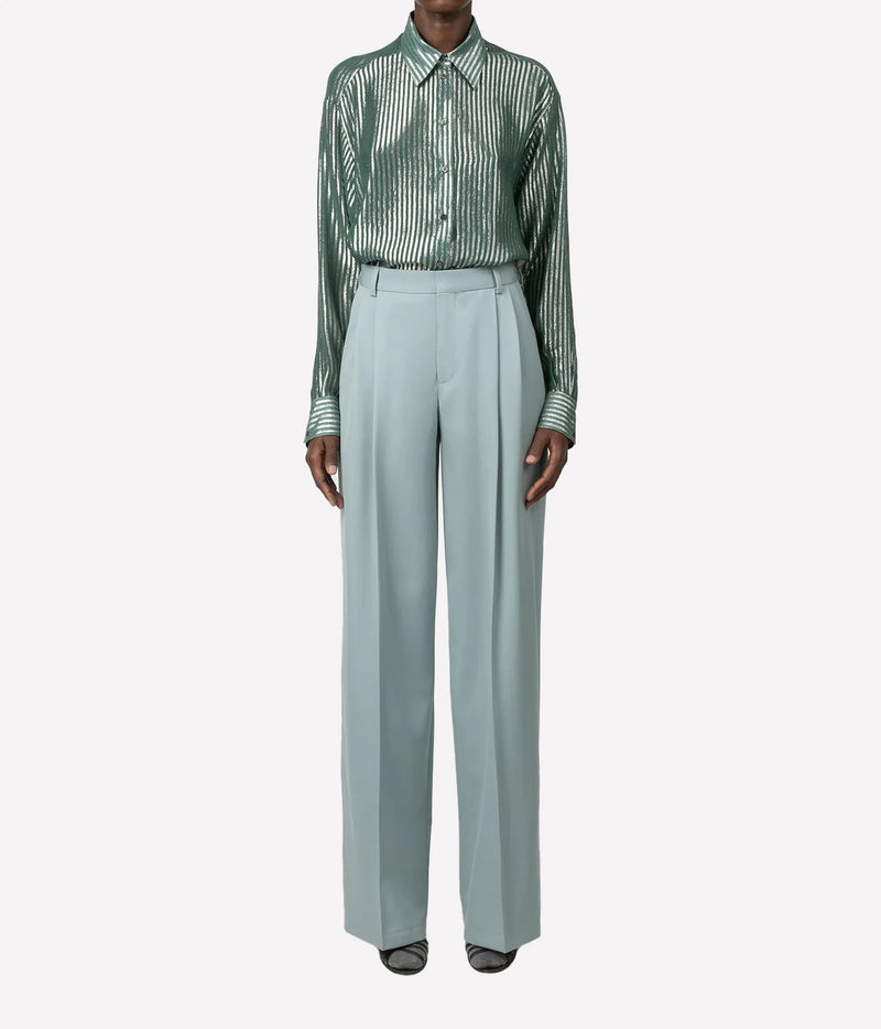 A model wearing a green and white vertically striped long-sleeve button-up shirt paired with high-waisted, wide-leg sage green trousers, shown against a plain light gray background.