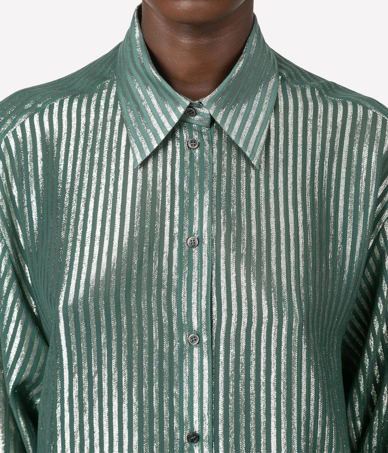 A close-up of a person wearing a collared button-front shirt with vertical metallic-looking stripes in green and white against a light gray background.