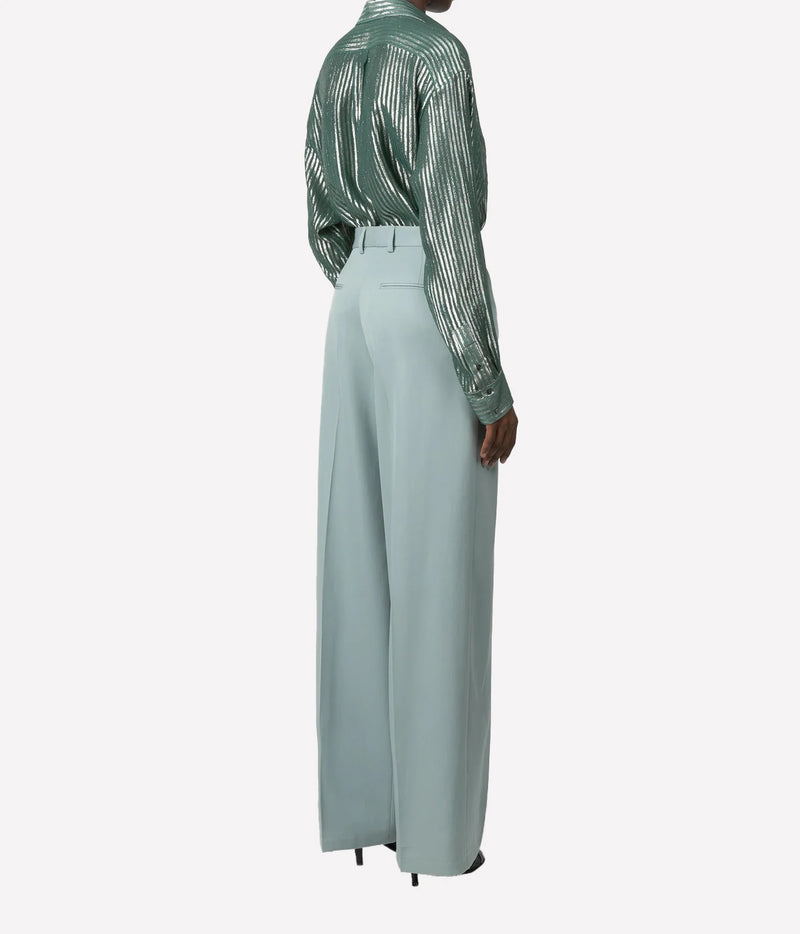 A model shown from the back wearing a sage green sequined long-sleeve shirt and light sage green wide-leg trousers, set against a plain light gray background.