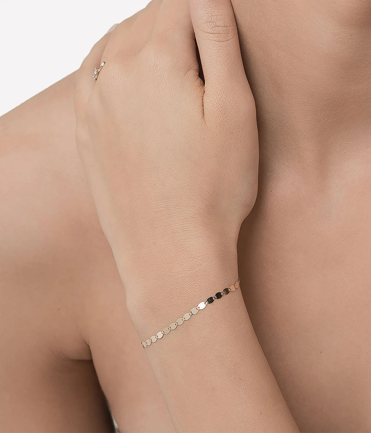 Model wearing the LANA Nude Chain Bracelet in Yellow Gold on her wrist, with the slim chain sitting close to the wrist bone