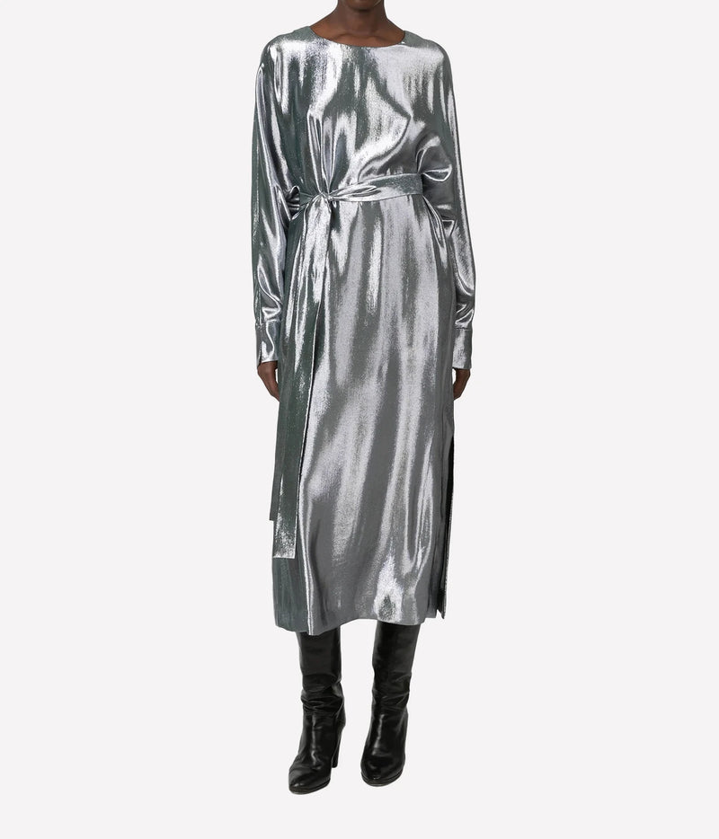 A long-sleeved metallic silver midi dress with a matching waist tie belt, worn by a model with black leather knee-high boots against a light gray background.