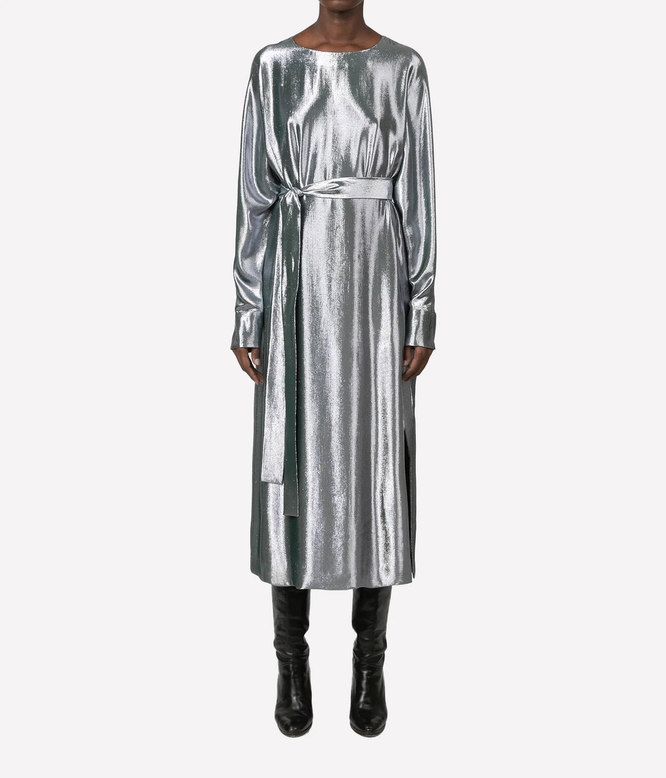 A model wearing a long-sleeved metallic silver midi dress with a matching waist tie belt, paired with black knee-high boots, against a plain light gray background.