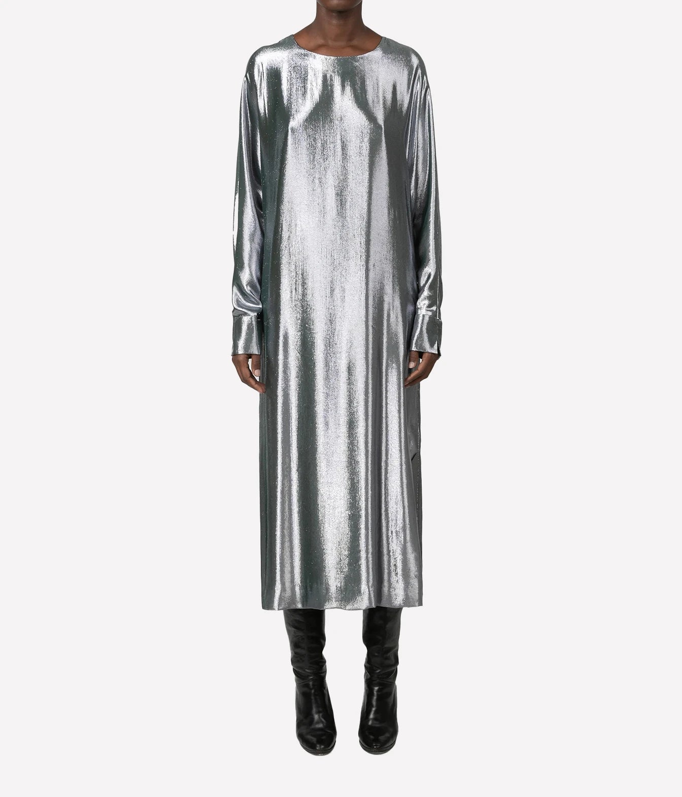 A model wearing a long-sleeved, midi-length metallic silver dress with a crew neck, paired with black knee-high boots, against a plain light gray background.