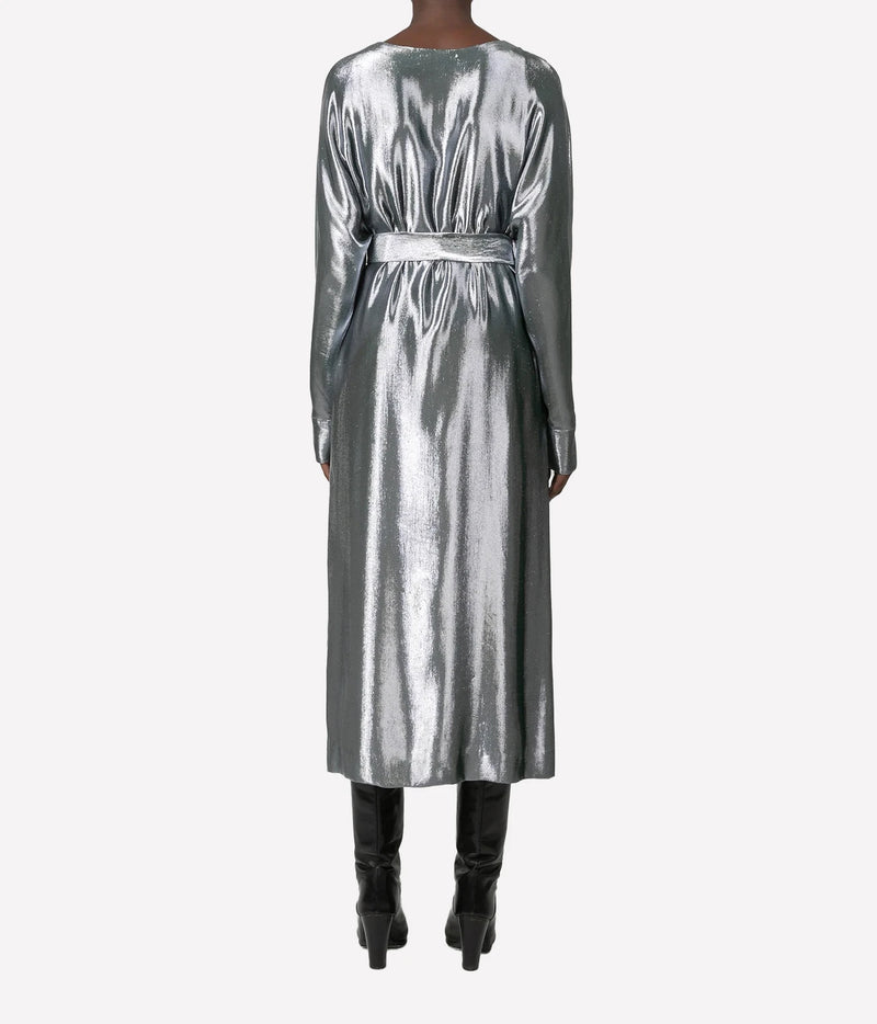 A model viewed from the back wearing a long-sleeved metallic silver midi dress with a matching waist belt, paired with black knee-high boots, against a light gray background.