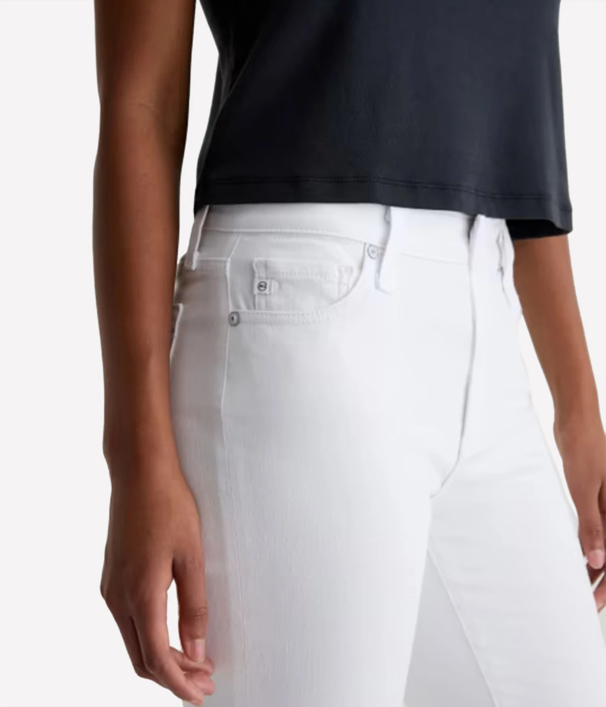 Person wearing a black top and white jeans on a plain background