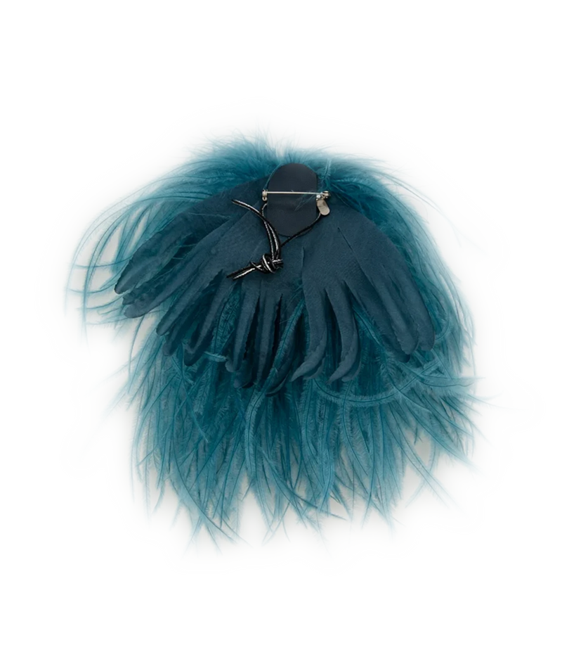 A teal blue tulle feather hair accessory with a dark blue fabric center and a silver metal claw clip, displayed on a plain white background.
