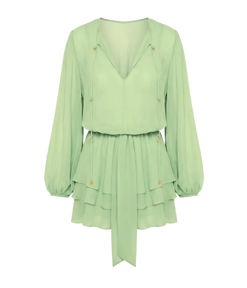 Alexis Milosia Dress In Pistachio shown flat from the front, showing the plunging V-neckline with neck ties, voluminous long sleeves with cuffs, tie waist with a long hanging sash and cascading layered mini hem