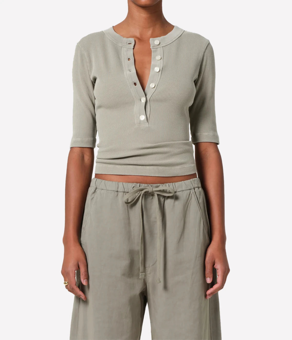 Person wearing a light khaki ribbed top and matching pants on a white background