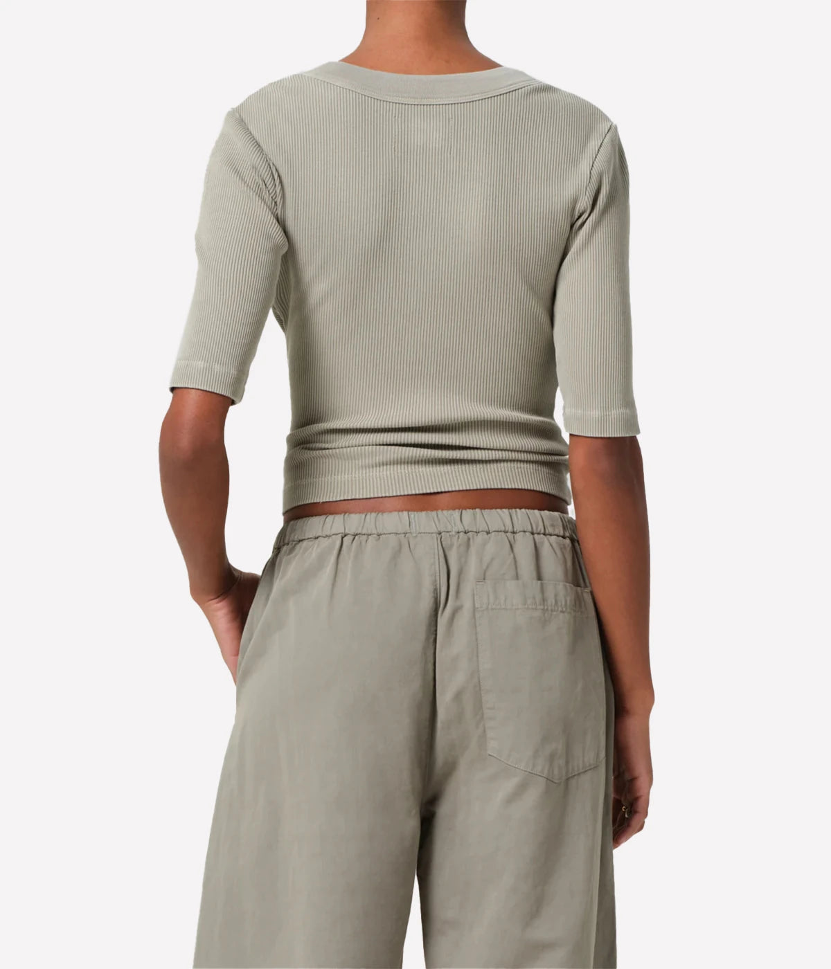 Person wearing a light khaki ribbed top and matching pants on a white background
