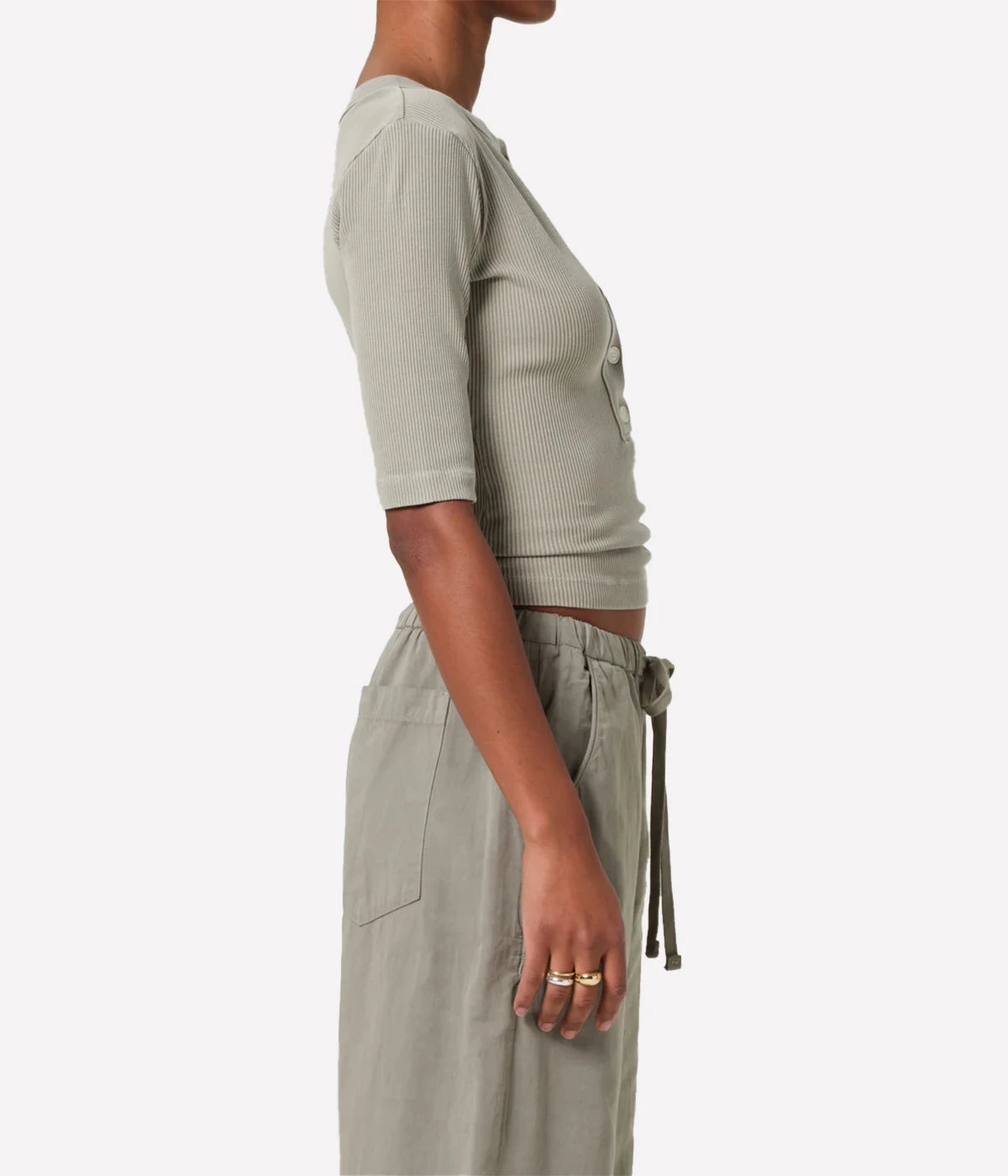 Person wearing a light khaki ribbed top and matching pants on a white background