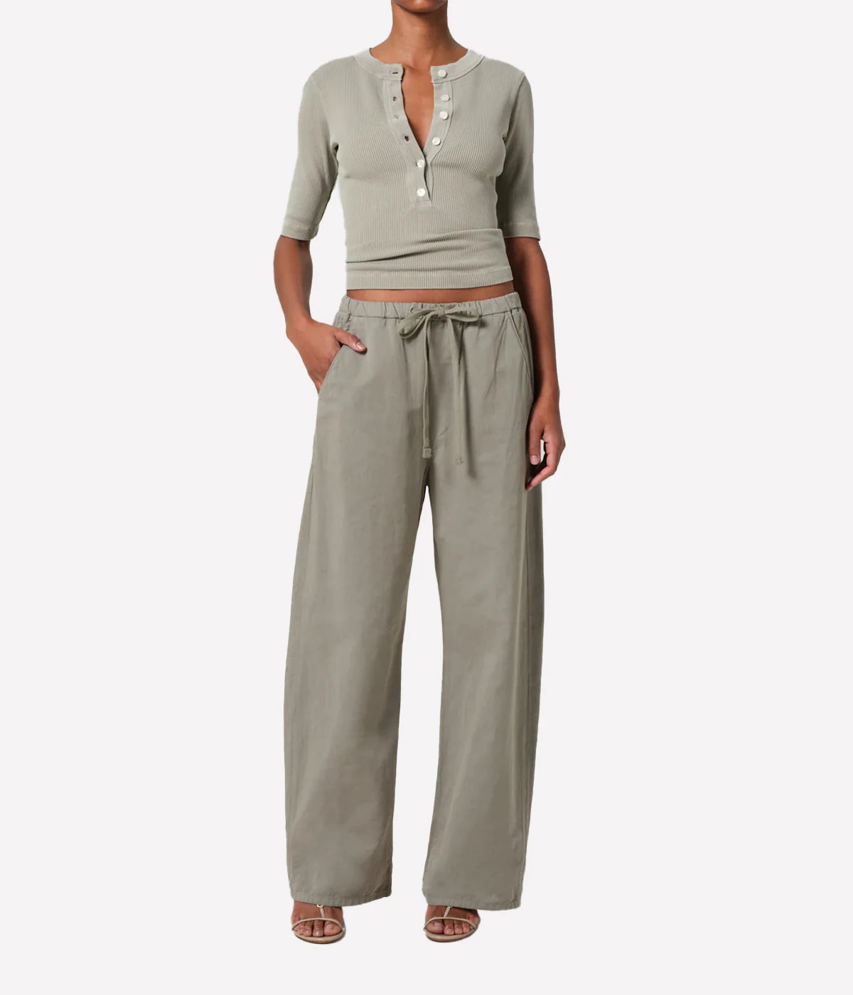 Person wearing a light khaki ribbed top and matching pants on a white background