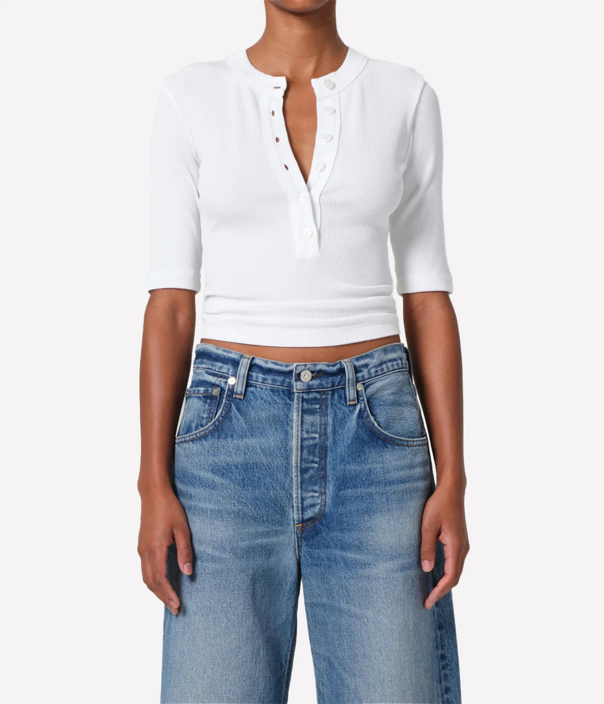 Person wearing a white cropped shirt and blue jeans on a white background