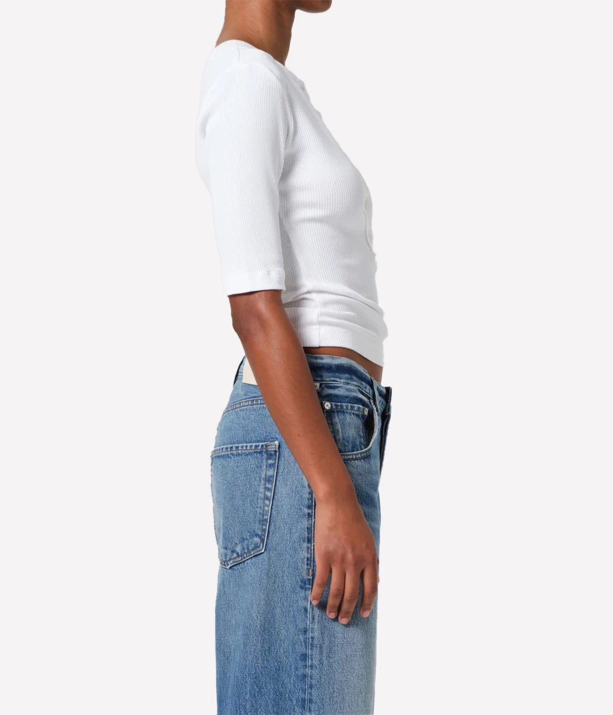 Person wearing a white t-shirt and blue jeans on a plain background