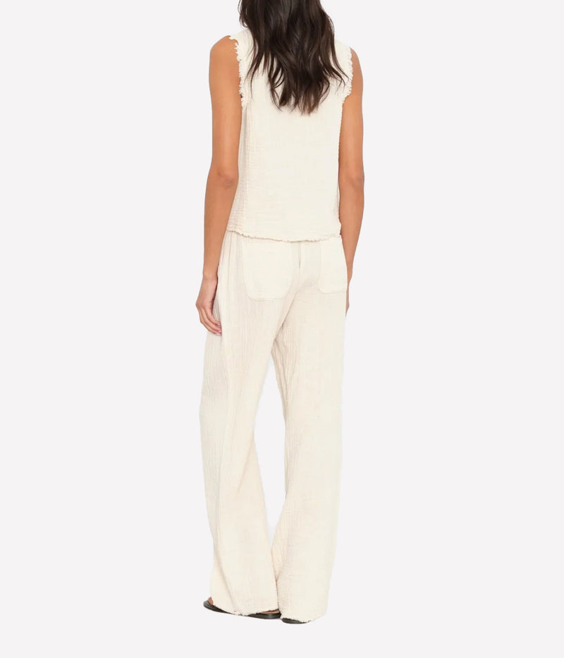 Back view of a model wearing the Xirena Joseph Pant in Oysterette with a matching sleeveless vest, showing the open back patch pockets and relaxed leg