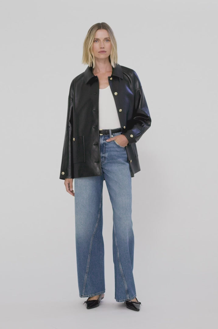 A video of a model wearing the Anine Bing Luca Jacket in Black Recycled leather showcasing the front and back of the jacket paired back with blue denim jeans and a slingback kitten heel.