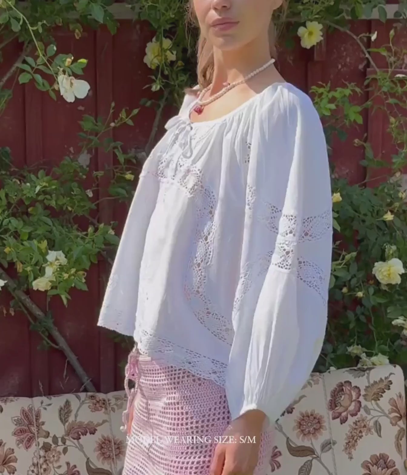 Model standing wearing the Sissel Edelbo Agathe Top In Ecru with pale pink skirt, showing the crochet lace insets and embroidery across the front
