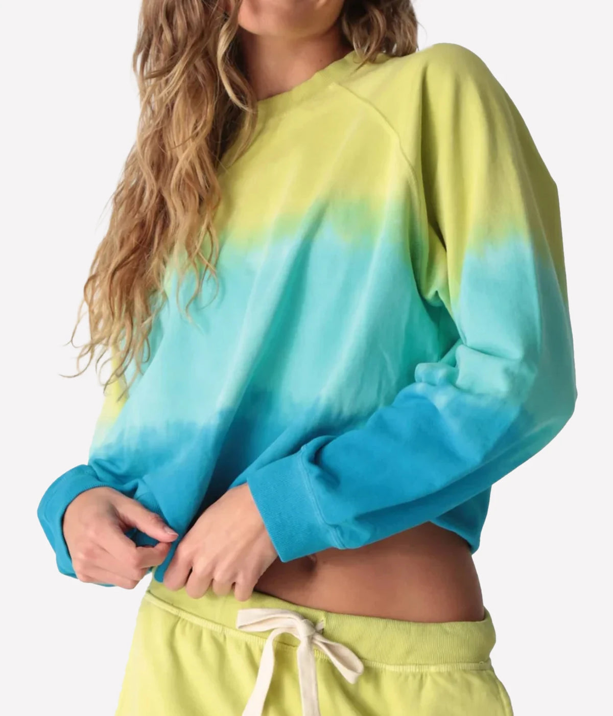 Side view of a model lifting the ribbed hem of the Electric Rose Ronan Ombre Sweatshirt in Chartreuse Multi 