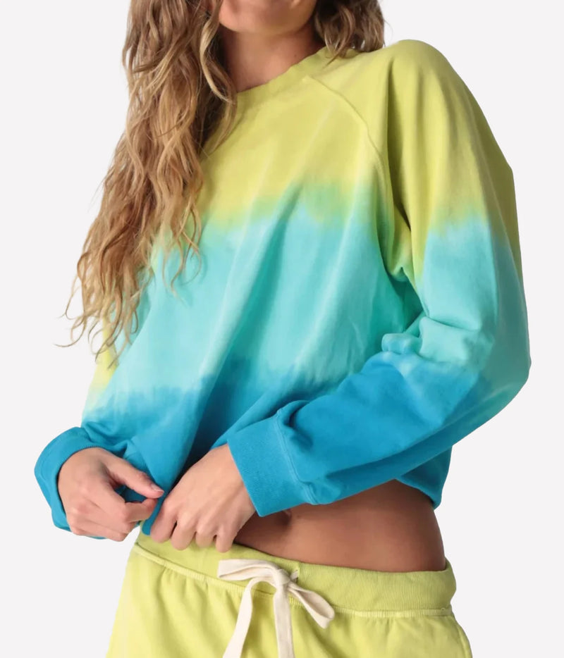 Side view of a model lifting the ribbed hem of the Electric Rose Ronan Ombre Sweatshirt in Chartreuse Multi 