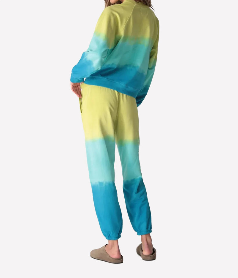 Back view of a model wearing the Electric Rose Ronan Ombre Sweatshirt in Chartreuse Multi with matching ombre joggers and taupe suede clogs