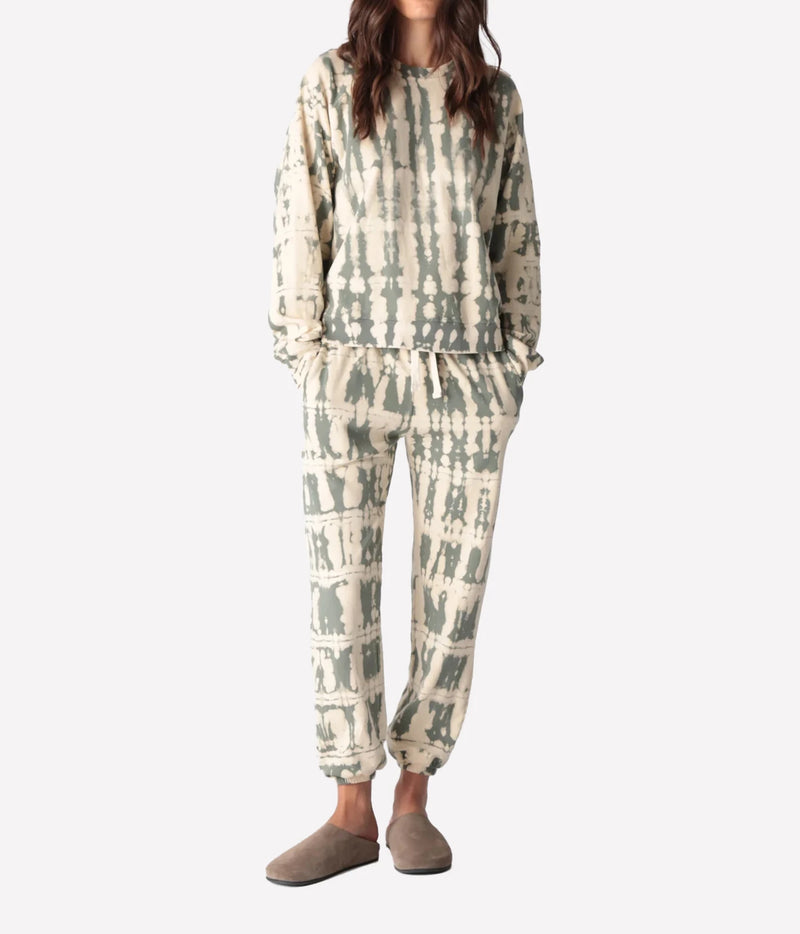 Full-length front view of a model wearing the Electric Rose Ronan Horizon Sweatshirt in Moss Ivory with matching tie-dye joggers, hands in pockets and taupe suede clogs