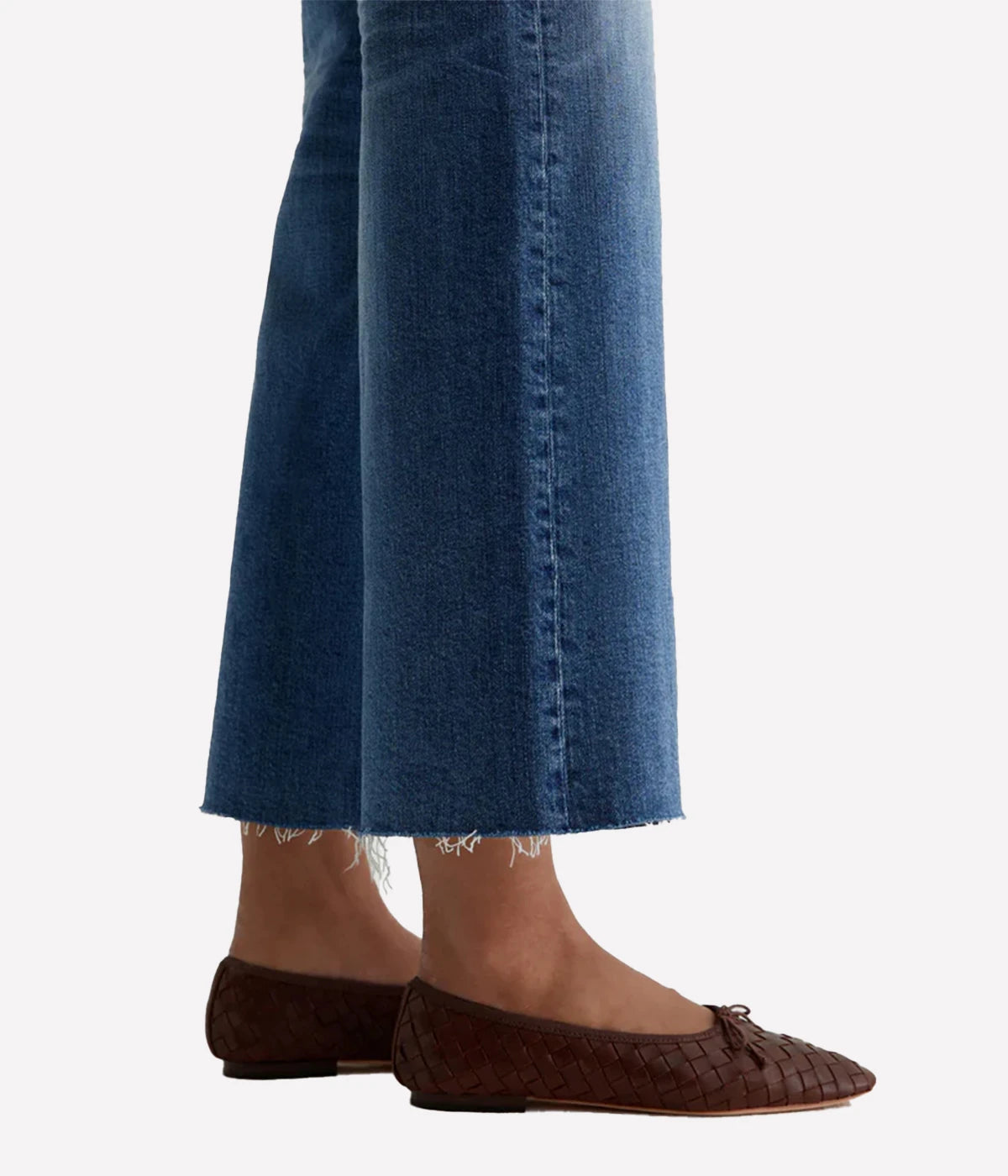 Person wearing blue jeans and brown flats on a white background