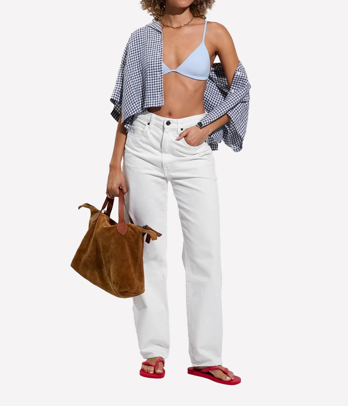 A model is shown from the waist down wearing white high-waisted jeans, a light blue bikini top, a blue-and-white gingham shirt draped off her shoulders, Sandy Top In Blue Skies