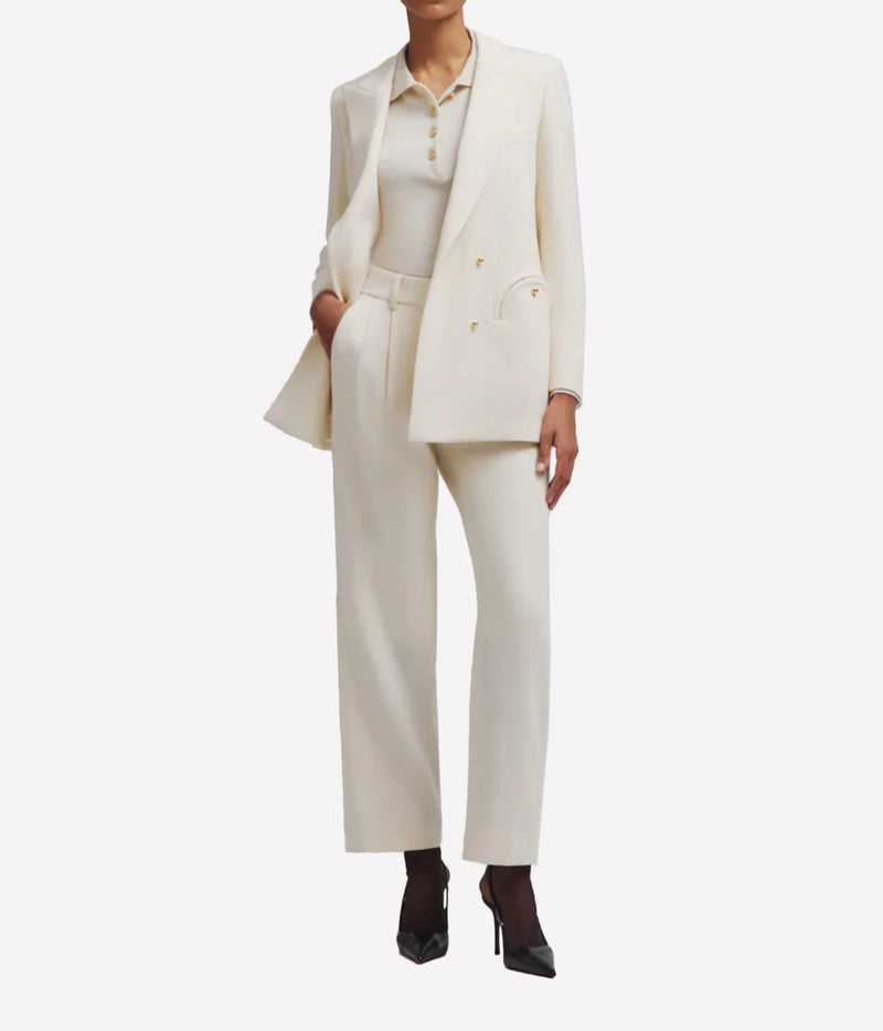 Model wearing the BLAZÉ Milano Resolute Everyday Double-Breasted Blazer in Cream buttoned with matching cream trousers and black ankle boots, front view