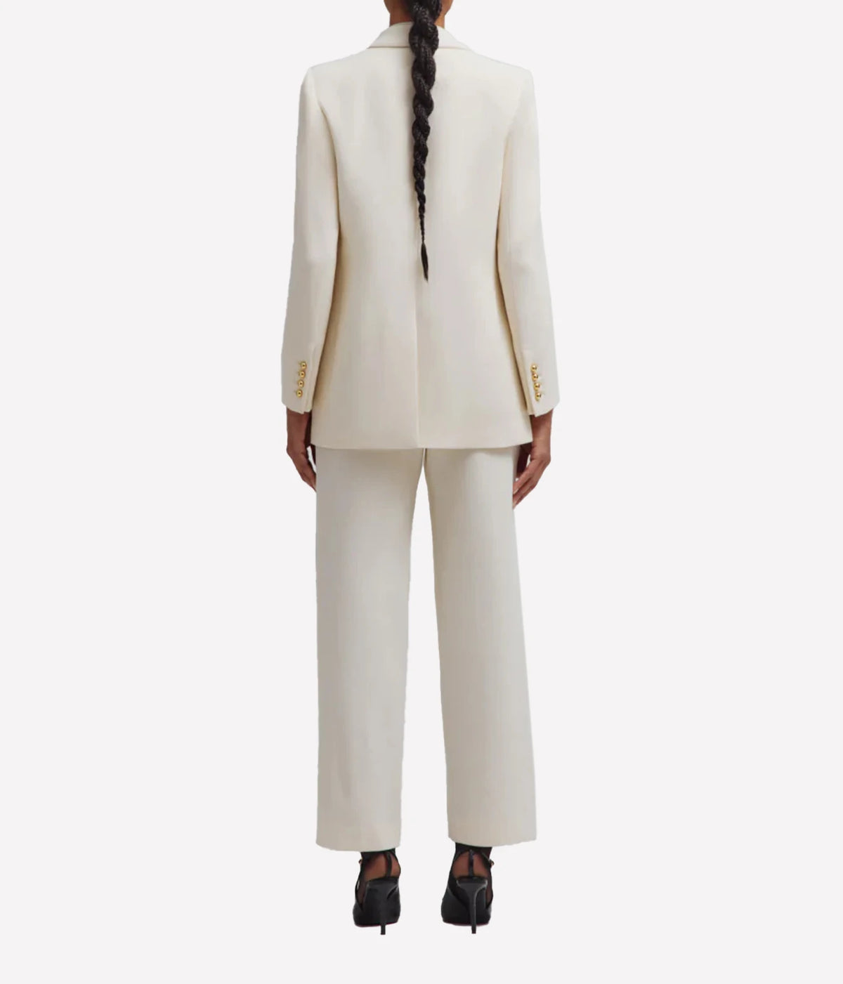 Back view of a model wearing the BLAZÉ Milano Resolute Everyday Double-Breasted Blazer in Cream with matching cream trousers and black ankle boots