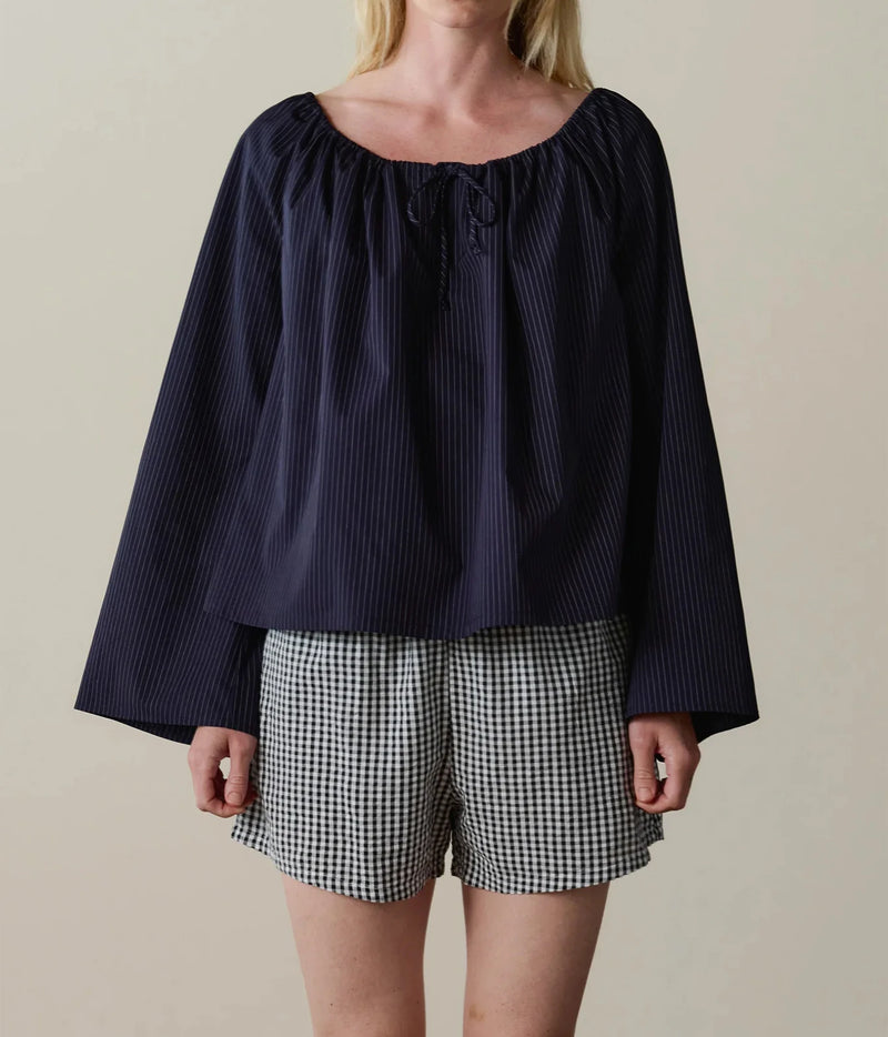 Model wearing navy gingham check shorts with a navy long-sleeve top, front view.