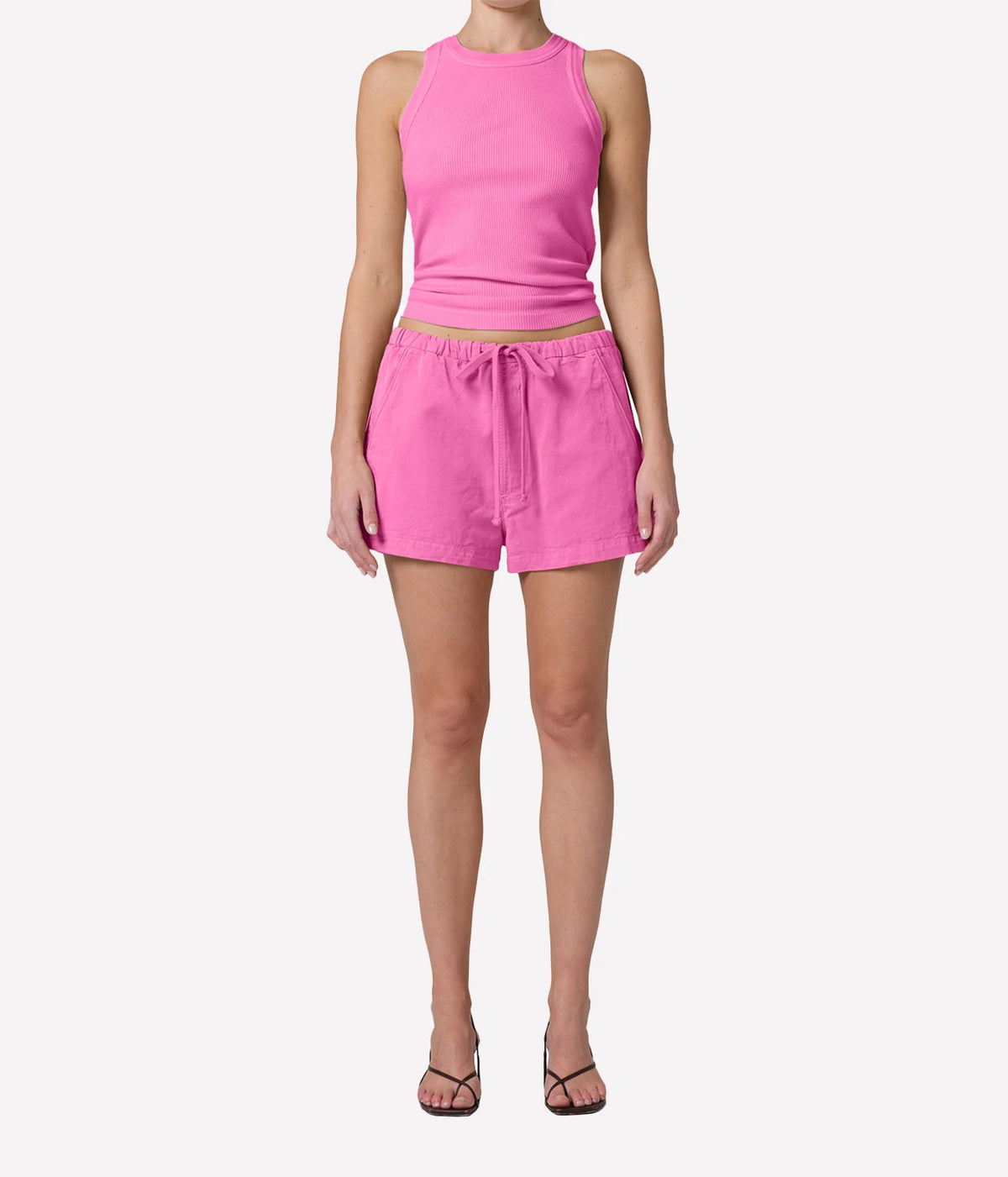 A model wearing a bright pink sleeveless crop top and matching pink drawstring shorts, Isabel Rib Tank in Raspberry