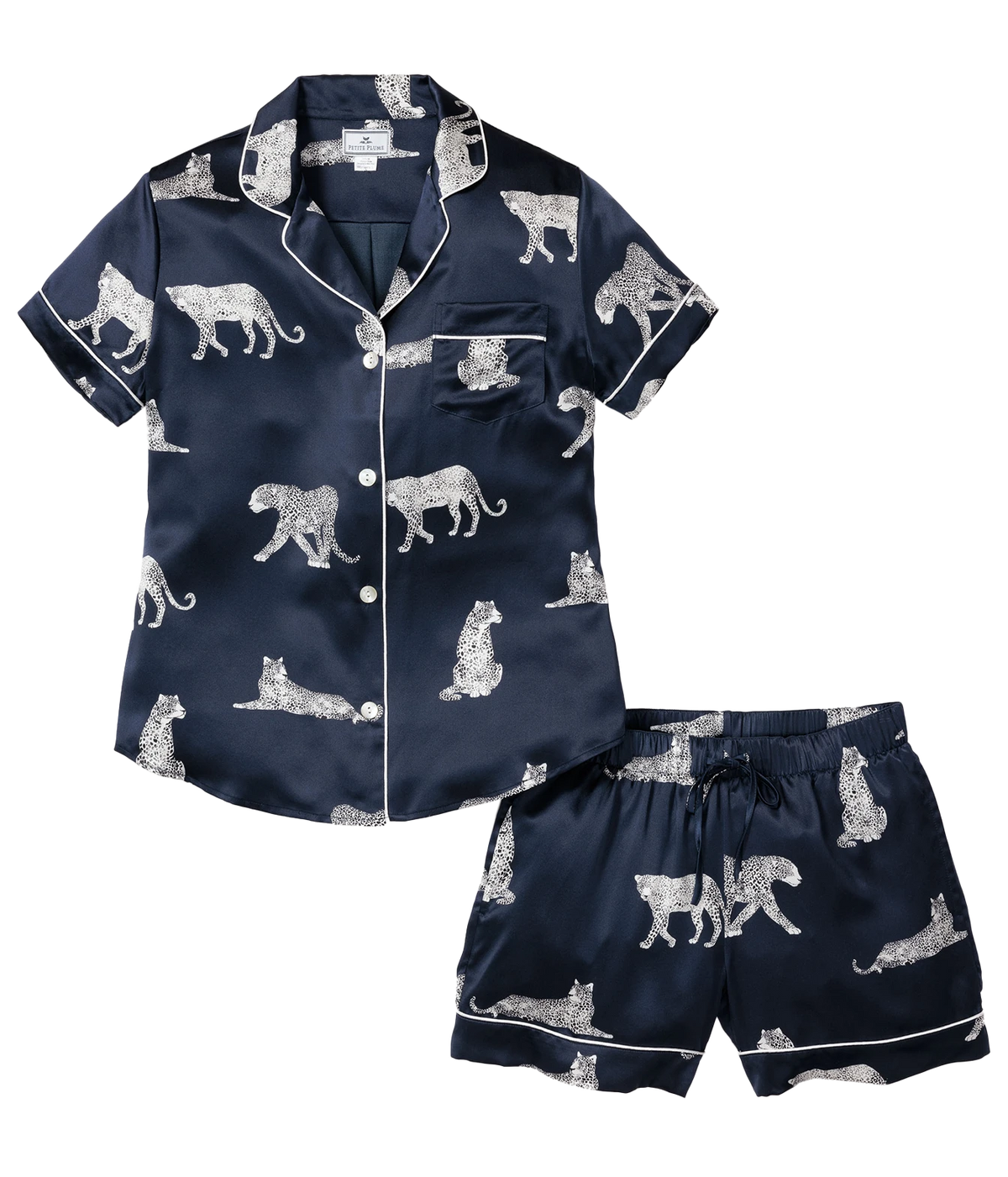 Petite Plume Mulberry Silk Short Pyjama Set in Panthère de Nuit laid flat, showing the short sleeve button front shirt with white piping and a chest pocket and the matching piped shorts in a white panther print