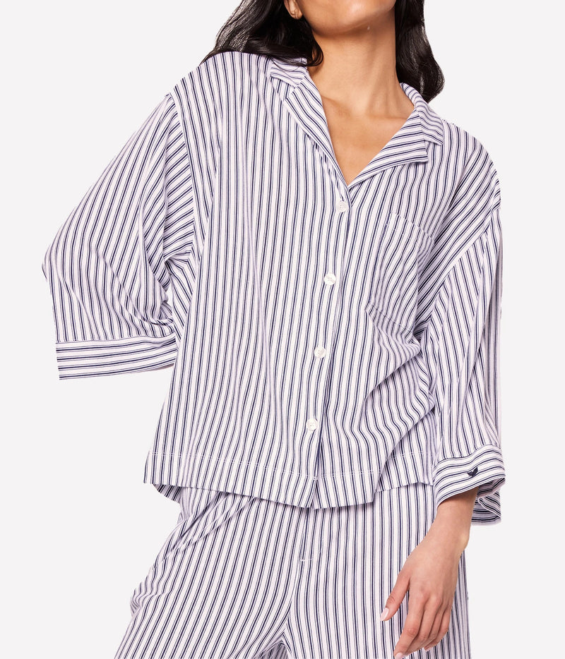 Close-up of a model wearing the Petite Plume Olivia Pima Long Pyjama Set in Navy, showing the notched collar, relaxed three-quarter sleeves and navy and white stripe