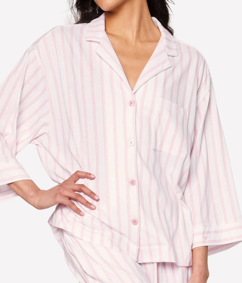 Model wearing the Petite Plume Olivia Pima Long Pyjama Set in Pink Stripe with the shirt buttoned and one hand on her hip, showing the relaxed fit and three-quarter sleeves