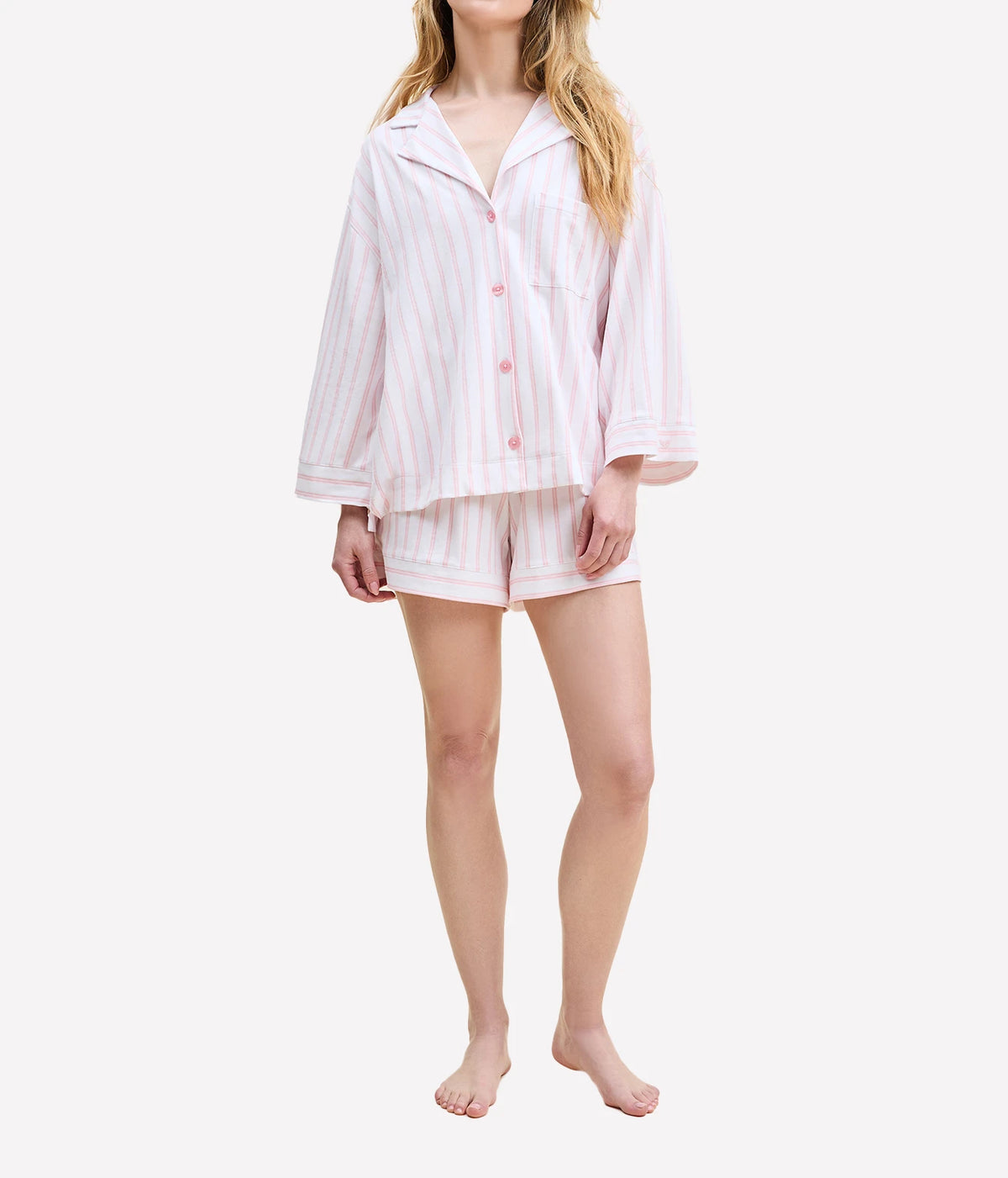 Front view of a model wearing the Petite Plume Olivia Pima Short Pyjama Set in Pink Stripes with the shirt buttoned and the shorts sitting at mid-thigh