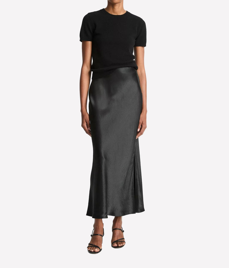 Woman wearing a black satin slip skirt with side slit, front view