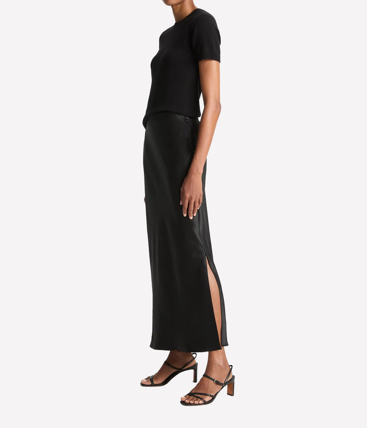 Woman wearing a black satin slip skirt with side slit, side view